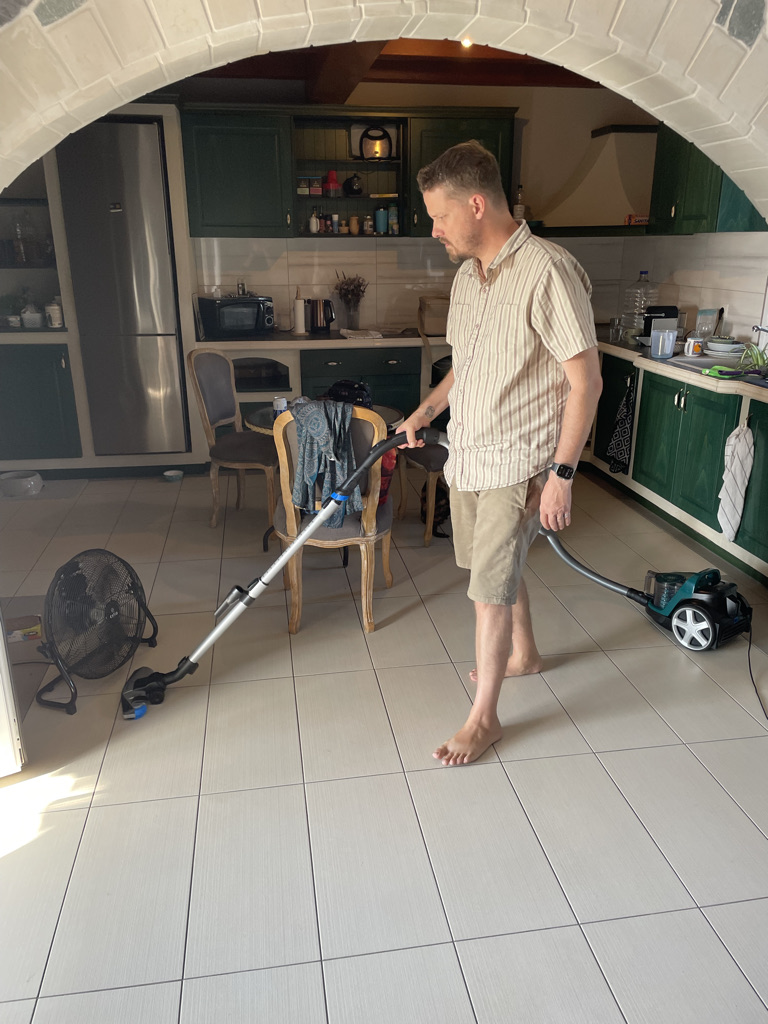 My husband happily trying out our new vacuum on our tile floor. Including evidence of our previous table, which was meant for the outdoors.