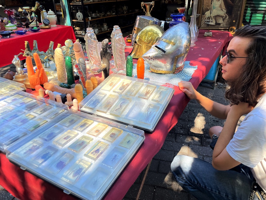 My son looking at a collection of penises on a flea market table