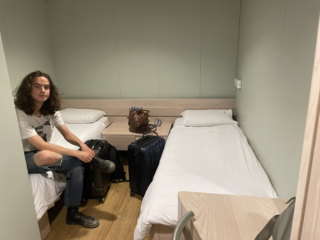 My son Felix sitting on a bed in our ferry cabin.