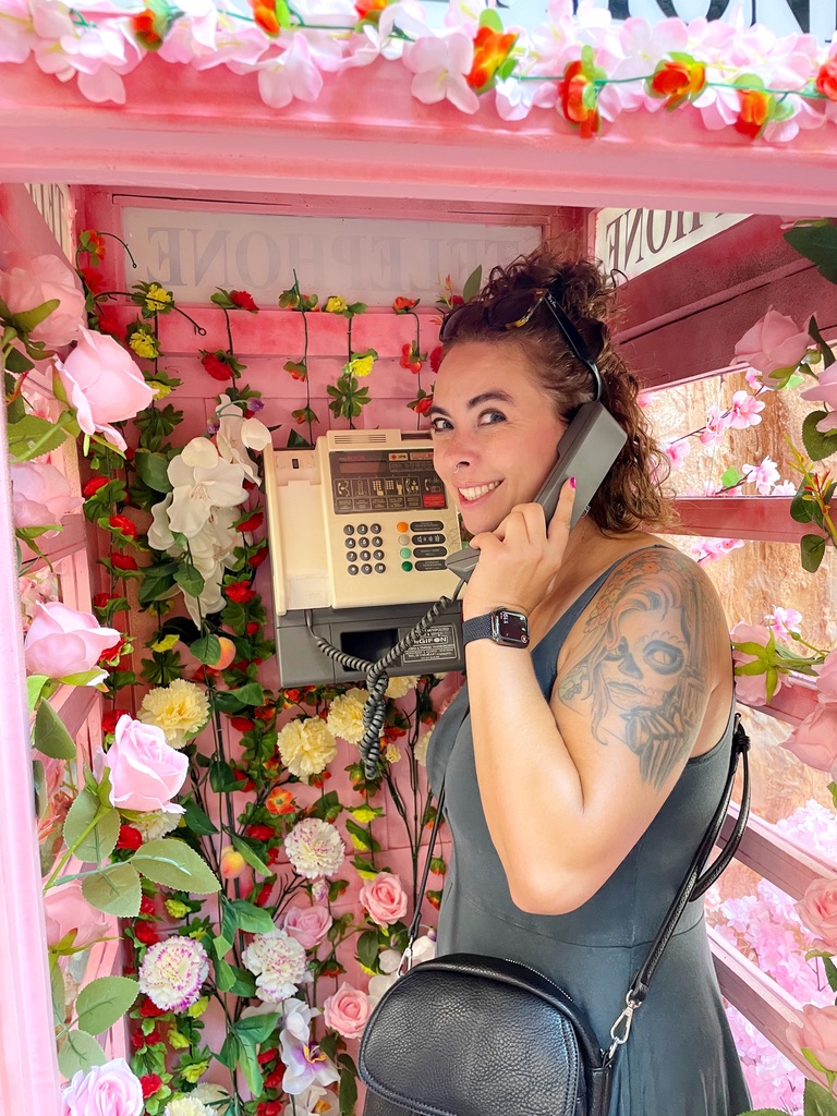 me making a call on an old phone in a phone both covered in flowers