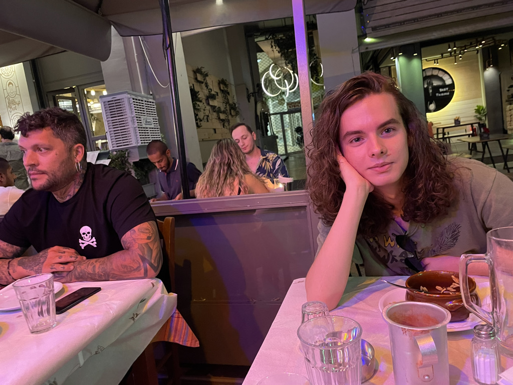 My son Felix sitting at a table on a taverna patio
